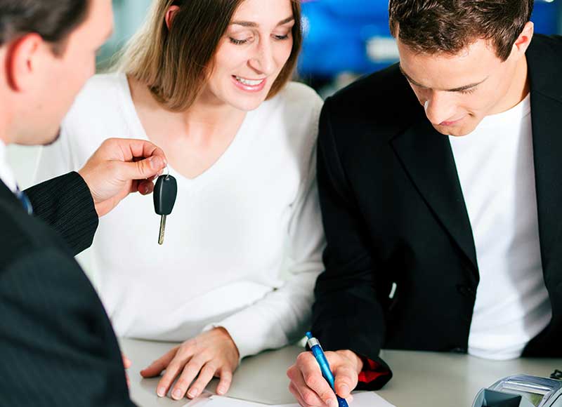 couple signing papers, salesman handing car key